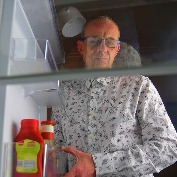 Un hombre sacando de la nevera un bote de kétchup. Fuente: Bigstock