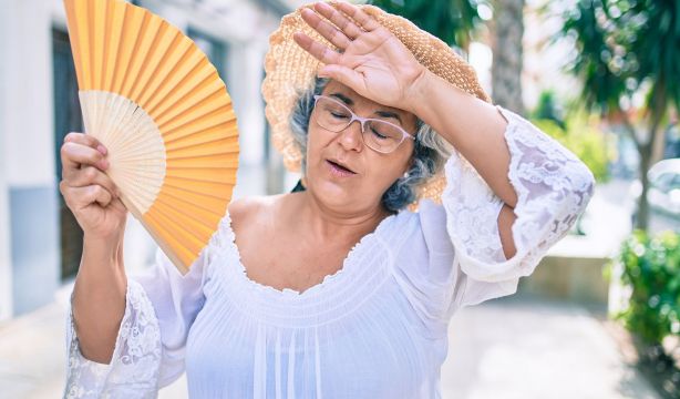 Mujer teniendo calor y ventilándose con un abanico