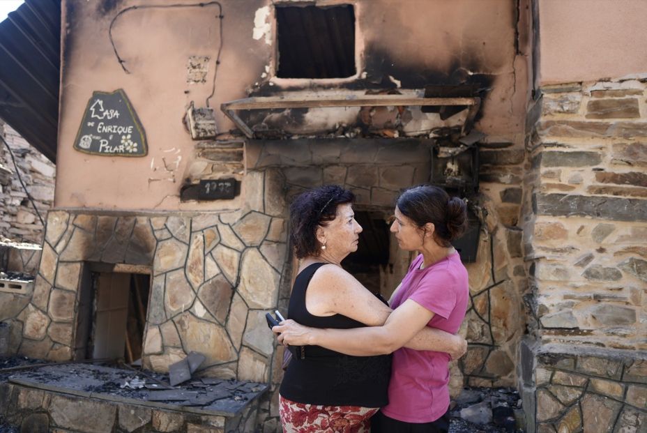 Dos vecinas se abrazan tras el incendio, a 22 de agosto de 2025, en San Vicente de Leira, Ourense, Galicia