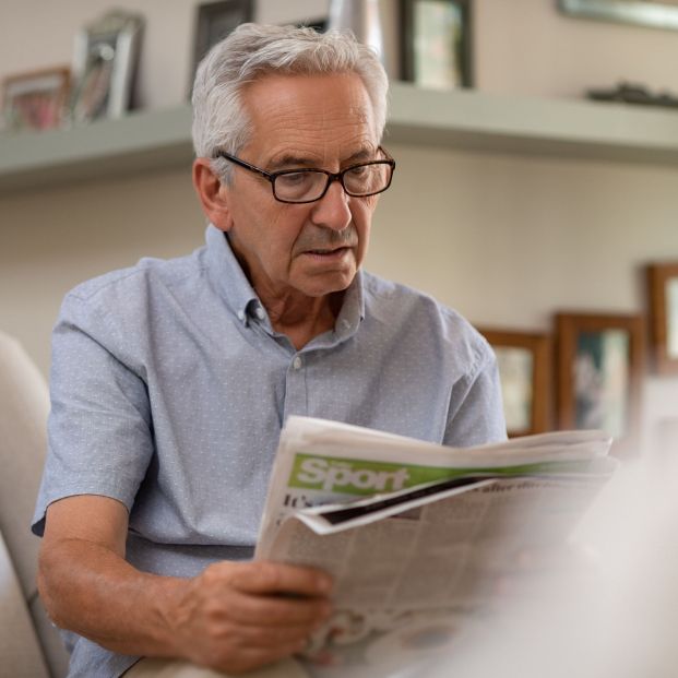 Persona adulta con gafas leyendo periódico a la distancia correcta Persona adulta con gafas leyendo periódico a la distancia correcta